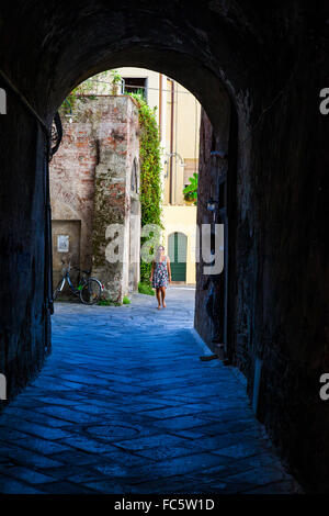 Frau zu Fuß hinunter einen Torbogen in Lucca, Toskana, Italien. Stockfoto