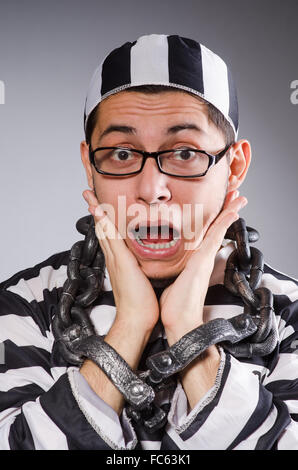 Jungen Gefangenen in Ketten gegen grau Stockfoto