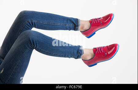 Frauenbeine In Blue Jeans und rote Schuhe Stockfoto