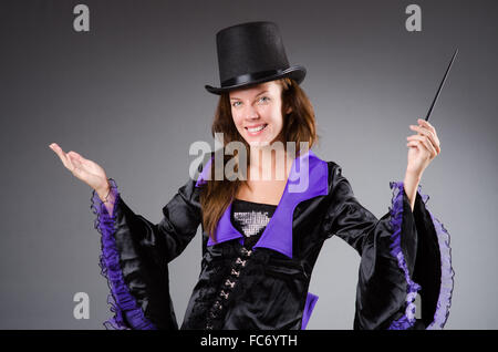 Hübsche Magier-Mädchen hält Stock gegen grau Stockfoto