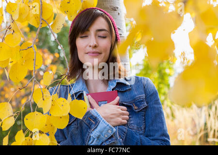 Hispanic Frau hält Tagebuch im Baum Stockfoto