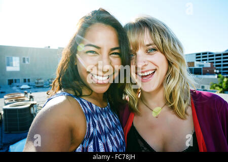 Frauen, die auf städtischen Dach umarmt Stockfoto