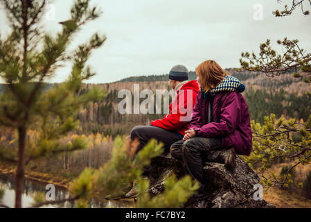Freunde sitzen auf Felsen auf abgelegenen Hügel Stockfoto