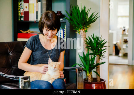 Kaukasische Frau Petting Katze im Wohnzimmer Stockfoto