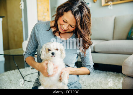 Kaukasische Frau Petting Hund im Wohnzimmer Stockfoto