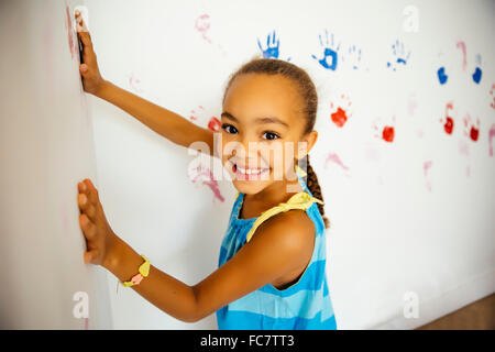 Gemischte Rassen Mädchen die Hand druckt auf Wand Stockfoto