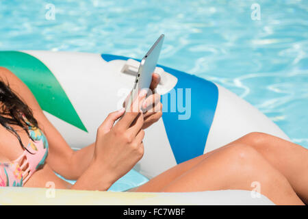 Kaukasische Frau mit digital-Tablette im Schwimmbad Stockfoto