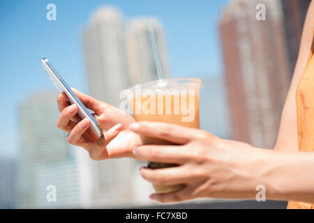 Hispanic Frau Holding Handy und Eiskaffee Stockfoto