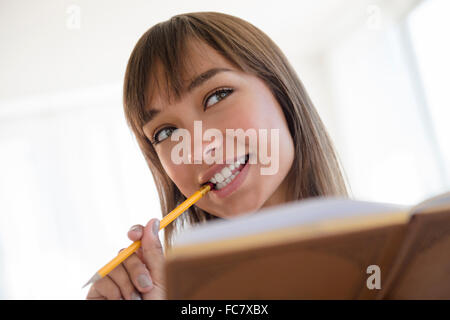 Gemischte Rassen Frau Bleistift kauen und lesen Stockfoto