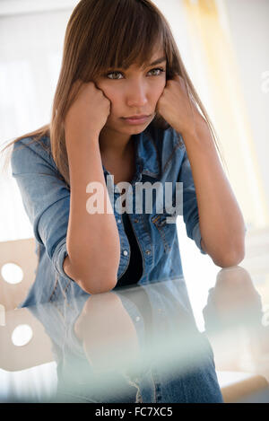 Gemischte Rassen Frau am Tisch schmollend Stockfoto