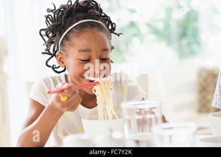 Schwarzes Mädchen essen Nudeln am Tisch Stockfoto