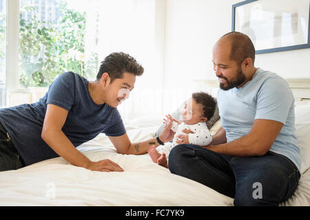 Schwule Väter spielen mit Baby Sohn auf Bett Stockfoto