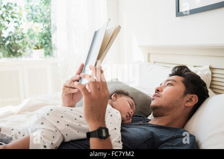 Vater mit schlafenden Baby Sohn lesen Stockfoto