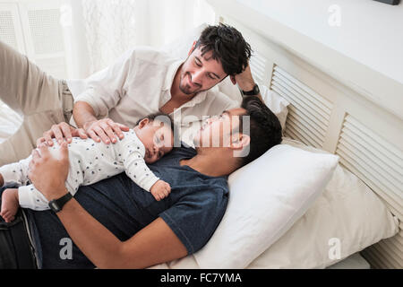 Schwule Väter mit Baby Sohn auf Bett entspannen Stockfoto