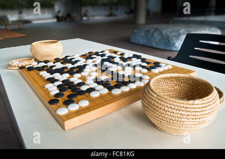 Endete Go-Spiel auf Holzbrett mit chinesischen Stil gespielt Stein Stücke, Steinen mit Kurve auf der einen Seite und auf der anderen Seite flach. Stockfoto