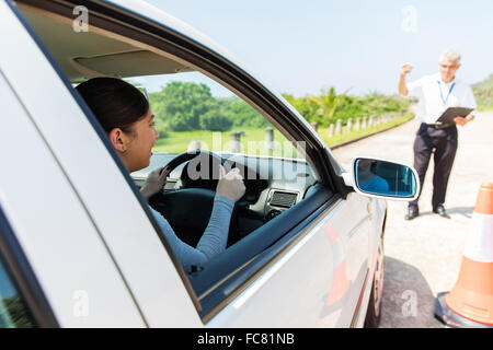 glückliche junge Studentin Fahrer mit Fahrlehrer lernen, ein Auto zu parken Stockfoto