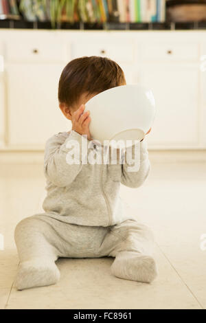 Gemischte Rassen Babyjungen trinken aus der Schüssel am Boden Stockfoto