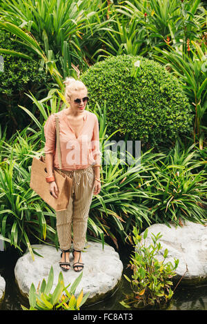 Kaukasische Frau auf Stein im Teich Stockfoto