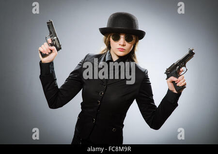 Spionin mit Waffe gegen grau Stockfoto