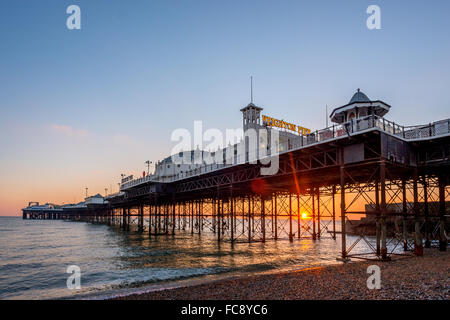 Die Sonne geht am Horizont hinter dem Palace Pier, Brighton. Stockfoto