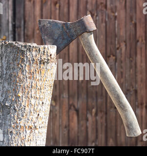 Bau und die Reparatur. Eine rostige Axt in einen Stub auf einem hölzernen Hintergrund. Stockfoto