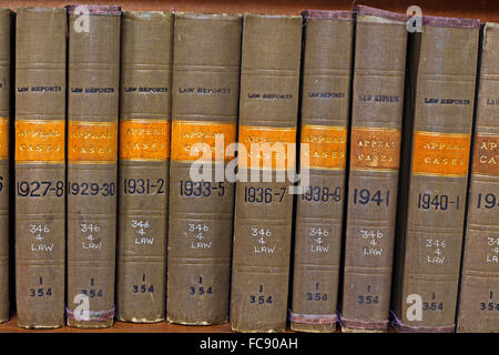 Eine Reihe alter, mit Stoff gebundener Gesetzesbände, die Titel und Jahre des Berufungsverfahrens zeigen, ordentlich auf einem hölzernen Bücherregal angeordnet. Stockfoto