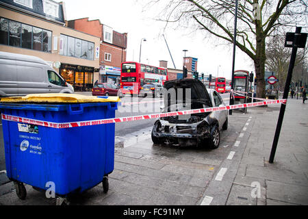 London, UK, 21. Januar 2016. Ein Ford-Auto Feuer fing außerhalb Tesco Express auf Holz grün High Road am frühen Morgen.  Rauch immer noch obwohl der verbrannten Motor und die Schriftart des Autos. Polizei abgesperrt das ausgebrannte Auto mit Polizei Klebeband. Bildnachweis: Dinendra Haria/Alamy Live-Nachrichten Stockfoto