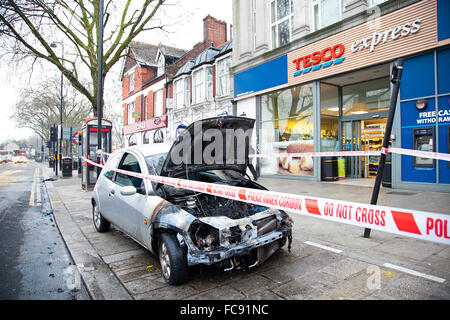 London, UK, 21. Januar 2016. Ein Ford-Auto Feuer fing außerhalb Tesco Express auf Holz grün High Road am frühen Morgen.  Rauch immer noch obwohl der verbrannten Motor und die Schriftart des Autos. Polizei abgesperrt das ausgebrannte Auto mit Polizei Klebeband. Bildnachweis: Dinendra Haria/Alamy Live-Nachrichten Stockfoto