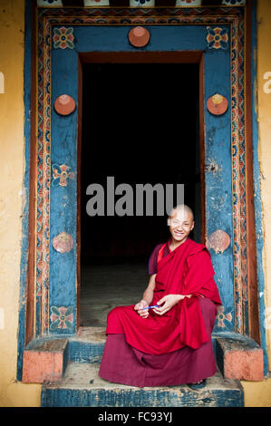 Junger Mönch sitzt in einem reich verzierten Tür, Punakha, Bhutan, Asien Stockfoto