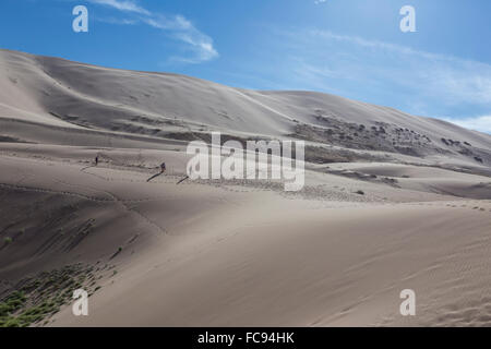 Weit entfernten Menschen eine riesige Sanddüne, schillernden auf eine Sommer-Abend, Khongoryn Els, Wüste Gobi, Mongolei, Zentralasien absteigend Stockfoto