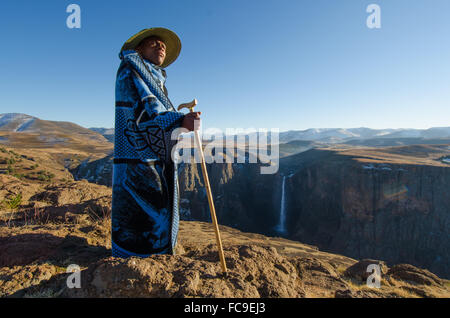 Ein lokaler Schafhirte konvergiert auf den Klippen der Maletsunyane-Wasserfall im ländlichen Lesotho. Stockfoto