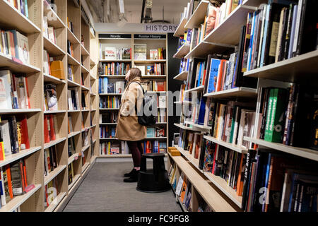 Junge Frau Surfen Bücher im Foyles Bookshop, Charing Cross Road, London, UK Stockfoto