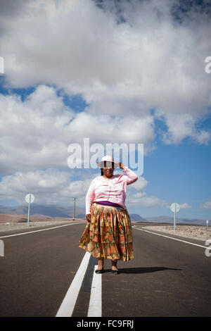 Ein Porträt einer traditionell gekleideten Frau mitten auf der Straße an einem klaren Tag in Bolivien. Stockfoto