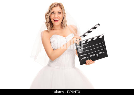 Fröhliche junge Braut im weißen Hochzeitskleid halten eine Filmklappe isoliert auf weißem Hintergrund Stockfoto