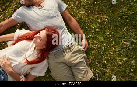 Junge Frau mit ihrem Freund auf dem Rasen liegen. Draufsicht des jungen Paares entspannende auf dem Rasen mit Textfreiraum. Stockfoto