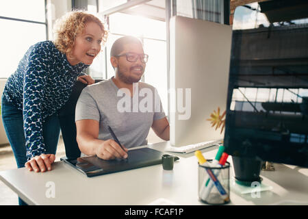 Zwei junge kreative Arbeiten zusammen an einem neuen Projekt im Büro. Männliche und weibliche Designer mit digitalen Grafiktablett und Stockfoto