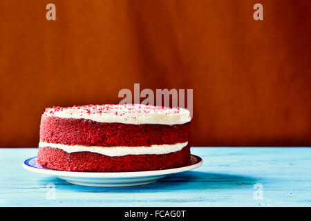 ein appetitlich roter Samt-Kuchen auf einem rustikalen Holztisch blau Stockfoto