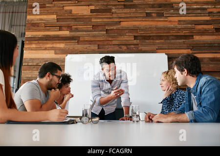 Brainstorming in einem Sitzungssaal Kreativbüro. Junge kreative Menschen am Tisch sitzen und neue Projekte zu diskutieren. Stockfoto