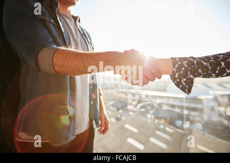 Nahaufnahme von Händeschütteln von Mann und Frau mit Objektiv flare. Handshake an einem sonnigen Tag im Mittelpunkt. Stockfoto