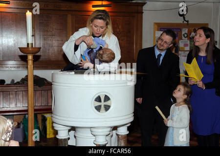 Taufe in St. Marien Kirche Caterham auf der Hill-Surrey England weibliche Priester Gießen Weihwasser auf Baby Boy mit Shell Stockfoto