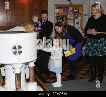 Taufe in St. Marien Kirche Caterham auf dem Hügel Surrey England Mädchen Taufe Kerze an der weiblichen Priester mit Elternteil übergeben Stockfoto