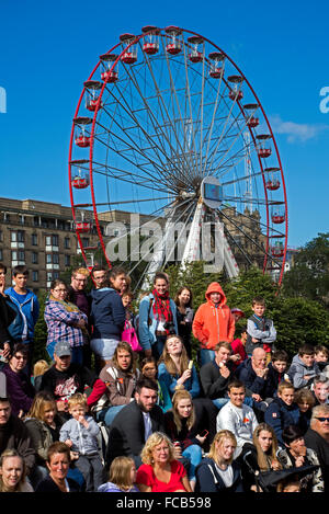 Eine Masse an der Edinburgh Fringe Festival sehen Sie ein Street Performer, während das Festival Rad im Hintergrund dreht. Stockfoto