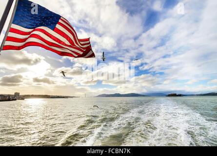 Blick auf die Bucht von San Francisco, Golden Gate Bridge, Möwen, die amerikanische Flagge winken und Alcatraz Island bei Sonnenuntergang von Stockfoto