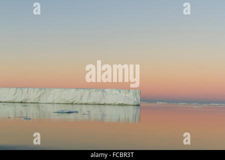 Tabellarischen Eisbergs spiegelt sich in ruhigen Gewässern der Antarktis Sound bei Sonnenuntergang. Stockfoto