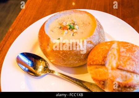 Nahaufnahme von einem Sauerteig Clam Chowder Gourmet-Teller. Eine cremige Suppe aus Muscheln und Gemüse serviert in einem Laib Brot von Abfuhrband Stockfoto