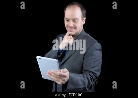 junger Mann dunklen grauen Anzug lächelnd Holding tablet Stockfoto