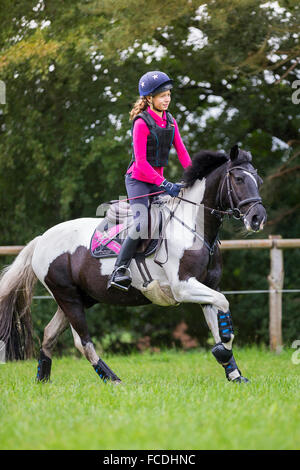 Pinto-Pony. Mädchen auf einem Skewbal Pony im Galopp auf dem Rasen bei einer Langlauf Fahrt. Deutschland Stockfoto