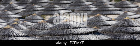 Detail der geflochtenen Sonnenschirme über Reihen am Strand in Zypern. Stockfoto