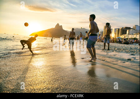 RIO DE JANEIRO - 18. Januar 2014: Gruppen von jungen Brasilianer spielen keepy uppy Strandfußball oder Altinho, bei Sonnenuntergang am Ufer Stockfoto