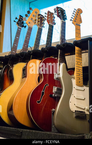 E-Gitarren, akustische Gitarren und elektrischen Bassgitarren auf einem Gestell in einem Tonstudio Stockfoto